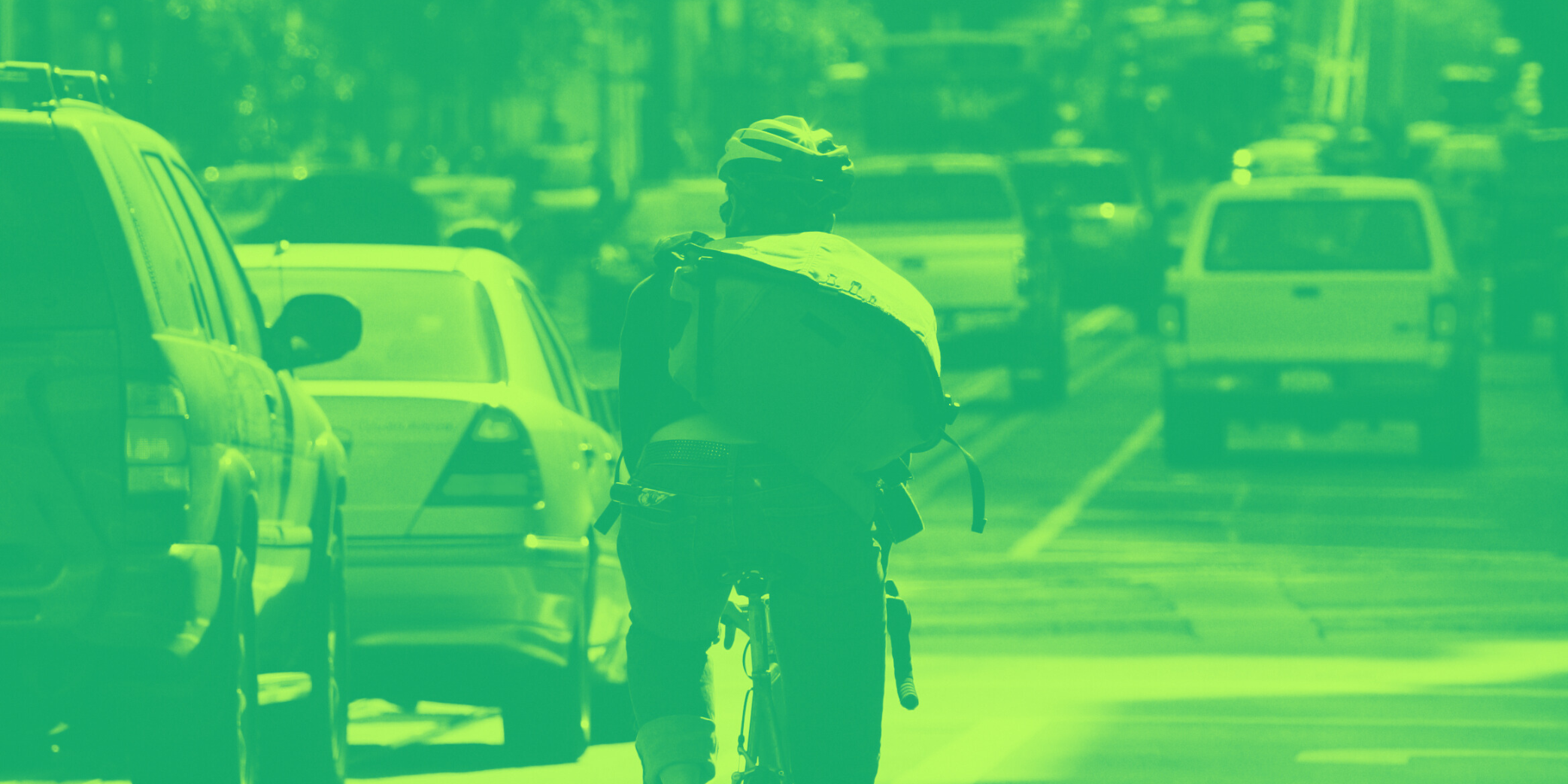lime green duotone image of a man riding a bike alongside street traffic