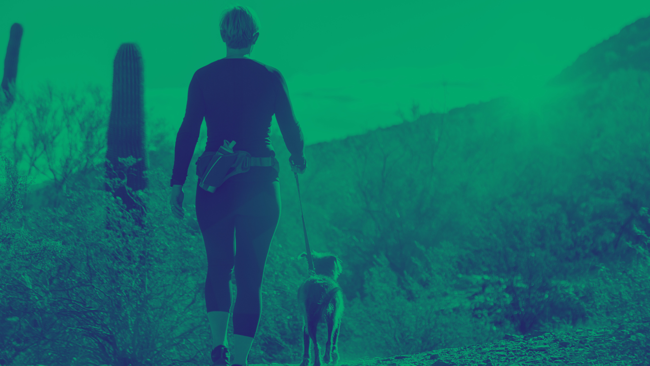 Duotone image of hiker walking with dog on a trail in Arizona